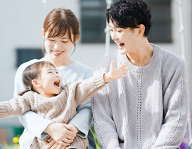 両手を広げて笑う女の子とほほ笑む両親の写真
