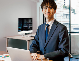 ノートパソコンの前に座って微笑む職員の写真
